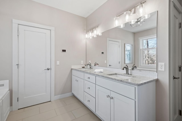 full bath featuring double vanity, tile patterned flooring, a sink, and baseboards