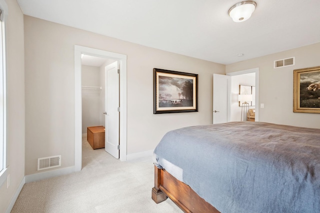 bedroom featuring light carpet, a spacious closet, visible vents, and baseboards