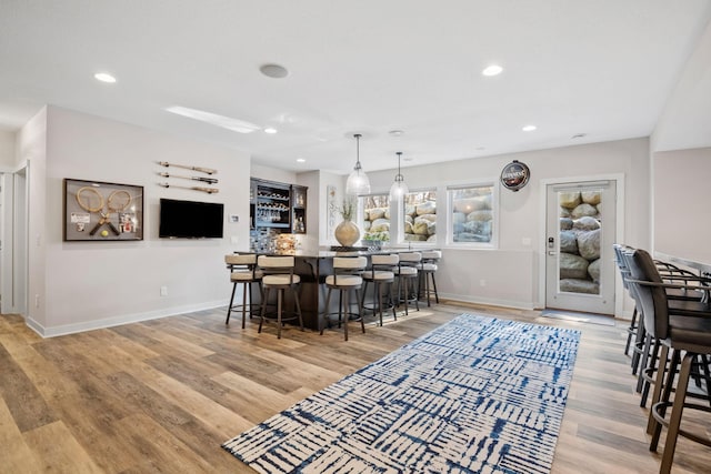 kitchen featuring baseboards, light wood-style floors, recessed lighting, and a kitchen breakfast bar