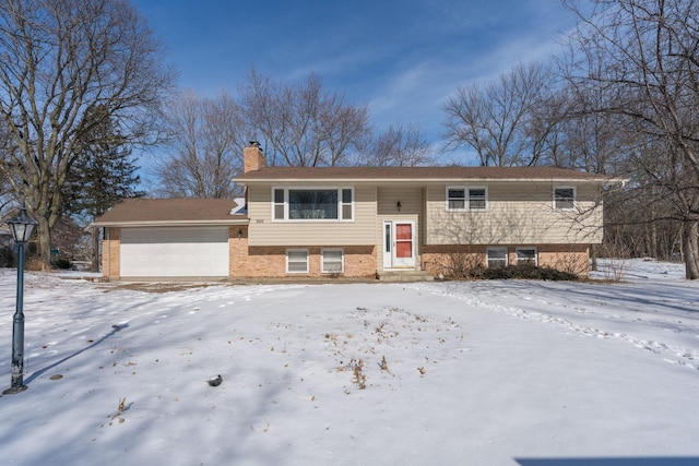 split foyer home with a garage, brick siding, and a chimney