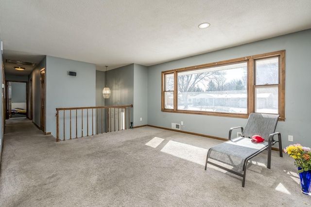 sitting room with a textured ceiling, light carpet, visible vents, and baseboards