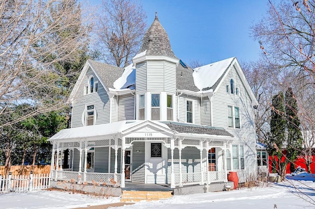 victorian-style house featuring a shingled roof, covered porch, and fence