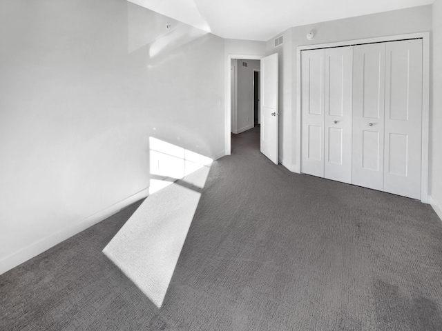 unfurnished bedroom featuring dark carpet and a closet