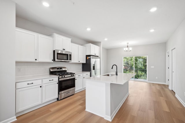 kitchen featuring stainless steel appliances, light wood finished floors, a sink, and decorative backsplash