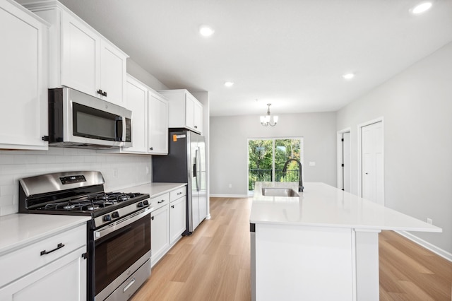 kitchen with white cabinets, appliances with stainless steel finishes, a sink, light countertops, and backsplash