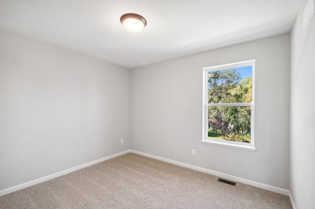 carpeted spare room with a textured ceiling, visible vents, and baseboards