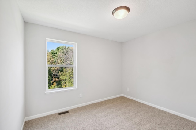 carpeted empty room with visible vents and baseboards