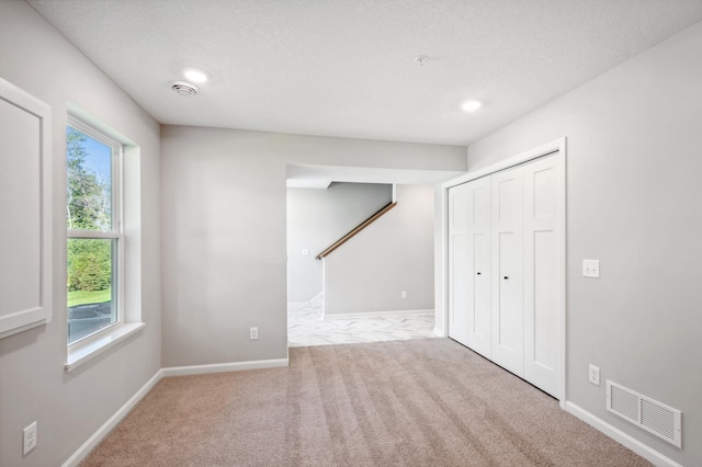 basement featuring baseboards, visible vents, a textured ceiling, and carpet flooring