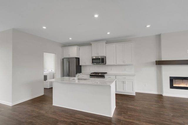 kitchen featuring a center island with sink, stainless steel appliances, tasteful backsplash, white cabinets, and a sink