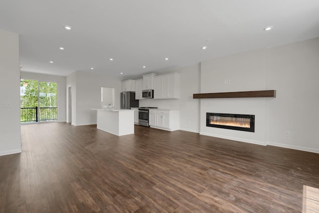 unfurnished living room featuring recessed lighting, baseboards, dark wood-style flooring, and a glass covered fireplace