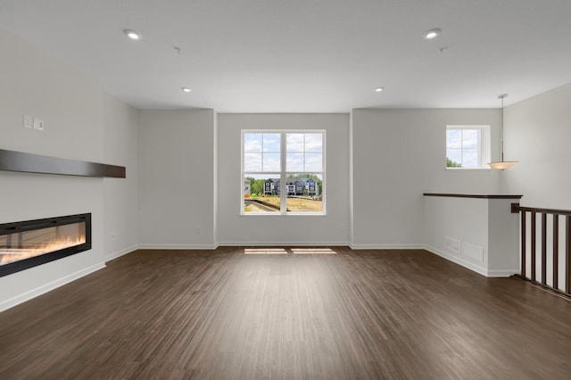 unfurnished living room with recessed lighting, baseboards, wood finished floors, and a glass covered fireplace