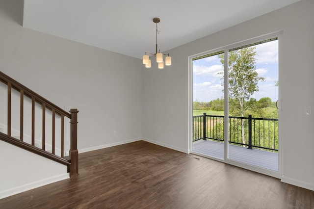 spare room featuring dark wood-style flooring, visible vents, baseboards, stairs, and an inviting chandelier