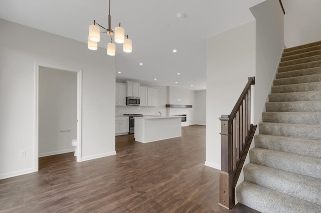 unfurnished living room with baseboards, dark wood finished floors, stairway, an inviting chandelier, and recessed lighting