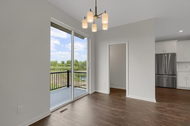 unfurnished dining area featuring dark wood-type flooring, a chandelier, visible vents, and baseboards