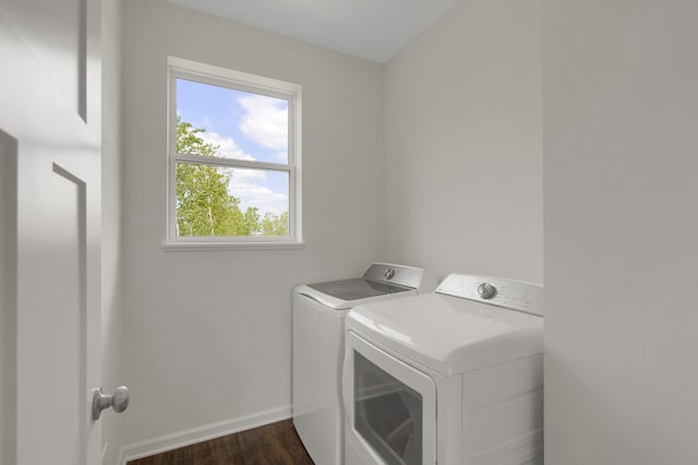 clothes washing area with dark wood-style floors, laundry area, washing machine and dryer, and baseboards