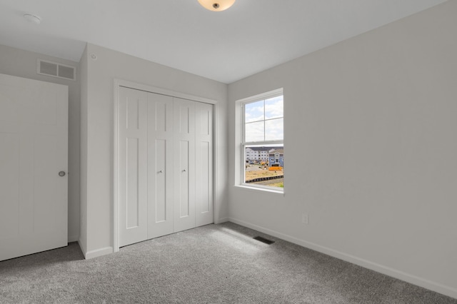 unfurnished bedroom featuring a closet, carpet, visible vents, and baseboards