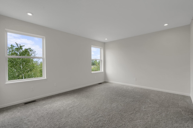 carpeted empty room featuring recessed lighting, visible vents, and baseboards