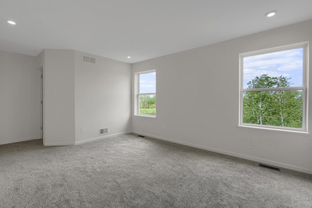 spare room with carpet floors, visible vents, and baseboards