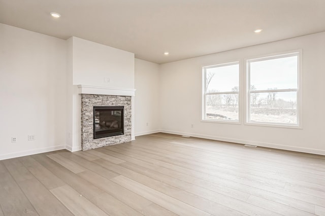 unfurnished living room with light wood-style floors, recessed lighting, a fireplace, and baseboards