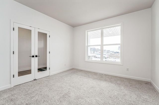 carpeted spare room featuring baseboards and french doors