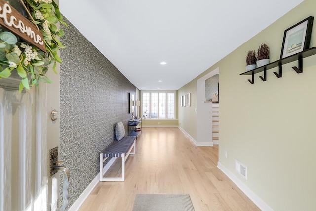 hall with recessed lighting, visible vents, light wood-style floors, baseboards, and stairs