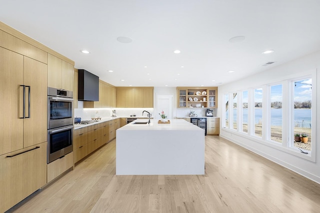 kitchen featuring white gas stovetop, light brown cabinetry, double oven, modern cabinets, and light wood-type flooring