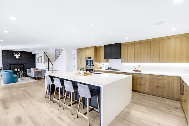 kitchen with light wood finished floors, a kitchen bar, modern cabinets, and white gas cooktop