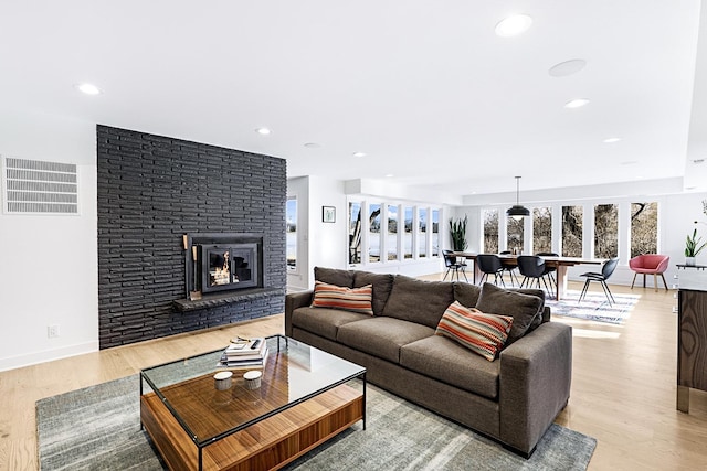 living room featuring light wood-type flooring, visible vents, and a wealth of natural light