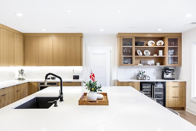 kitchen featuring modern cabinets, wine cooler, glass insert cabinets, a sink, and recessed lighting