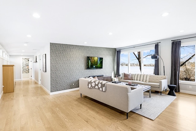 living room featuring recessed lighting, an accent wall, baseboards, light wood-style floors, and wallpapered walls