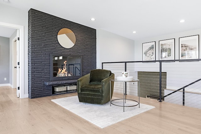 living area featuring a fireplace, baseboards, wood finished floors, and recessed lighting