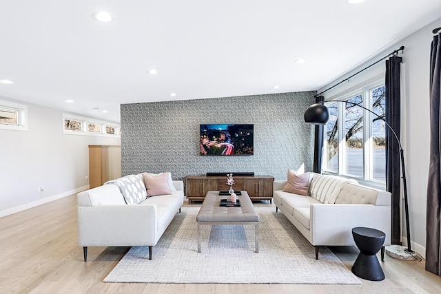 living room featuring light wood-style floors, an accent wall, baseboards, and recessed lighting