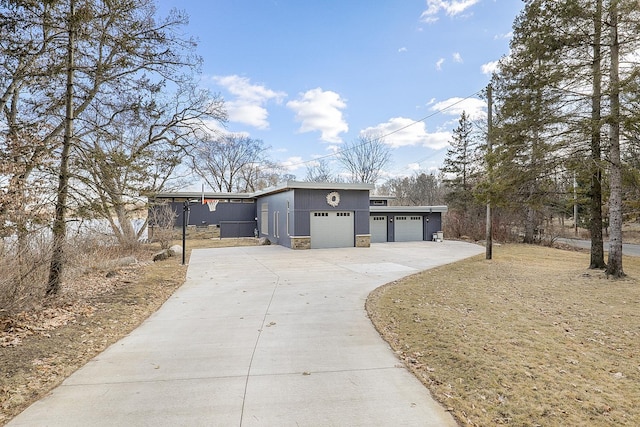 exterior space featuring a garage, stone siding, concrete driveway, and stucco siding