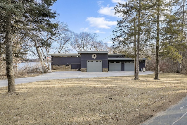 view of front of house featuring driveway, stone siding, an attached garage, and stucco siding