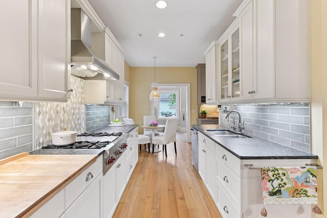4943 Dupont Ave S, Minneapolis, MN 55419 - kitchen featuring wall chimney range hood, light wood-type flooring, glass insert cabinets, white cabinets, and tasteful backsplash
