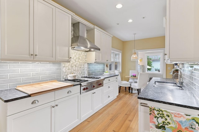 4943 Dupont Ave S, Minneapolis, MN 55419 - kitchen featuring wall chimney range hood, stainless steel gas cooktop, white cabinets, tasteful backsplash, and light wood-style flooring