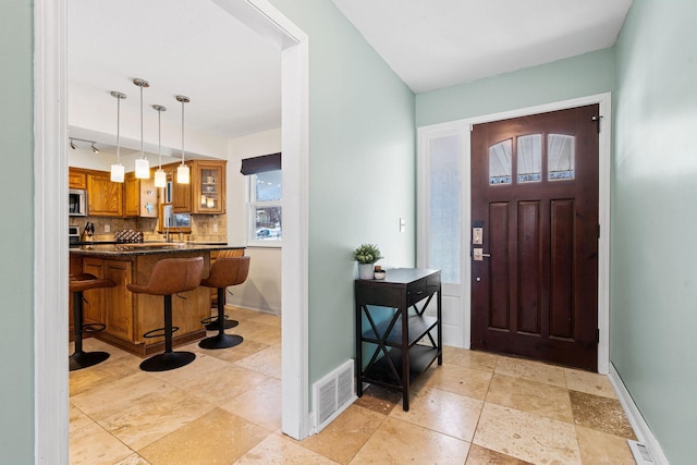 foyer entrance with visible vents and baseboards