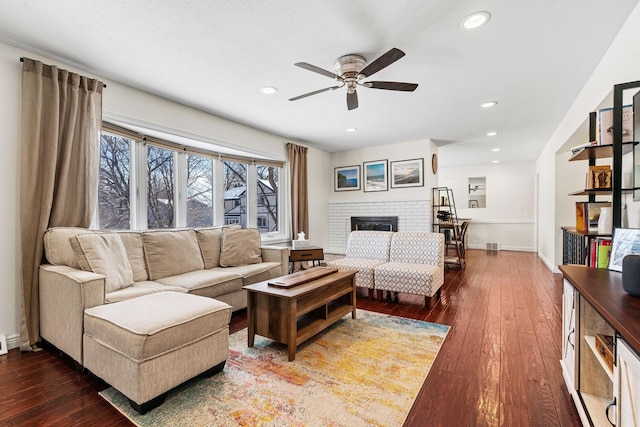 living room with recessed lighting, baseboards, a brick fireplace, and hardwood / wood-style floors