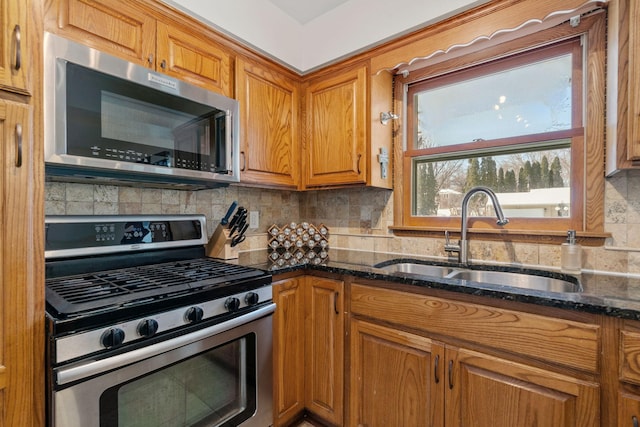 kitchen with tasteful backsplash, dark stone countertops, stainless steel appliances, and a sink