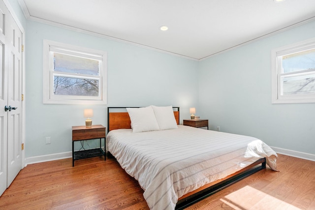 bedroom featuring multiple windows, light wood-style floors, and crown molding