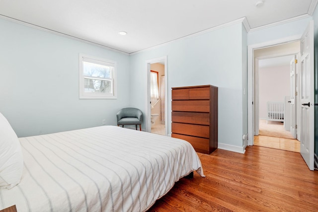 bedroom featuring connected bathroom, baseboards, wood finished floors, and ornamental molding