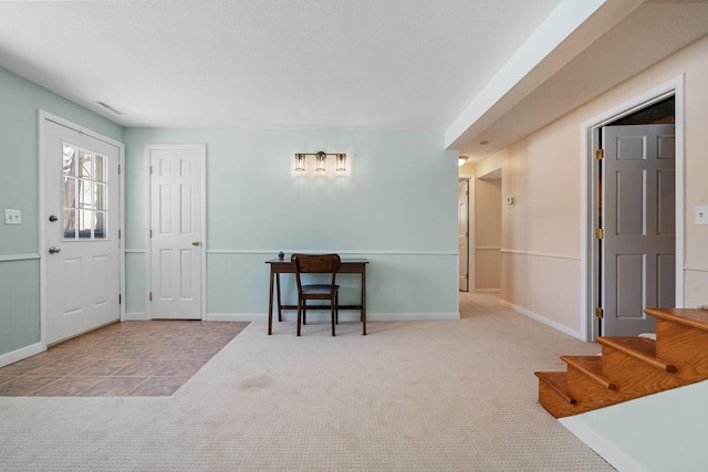 entrance foyer featuring a wainscoted wall, carpet, visible vents, and stairway