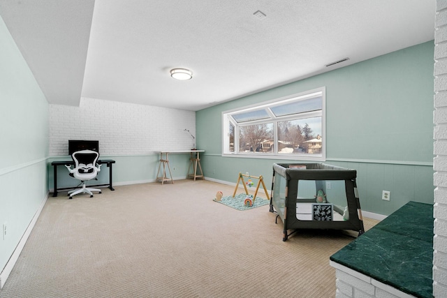 interior space featuring a textured ceiling, carpet flooring, visible vents, and wainscoting