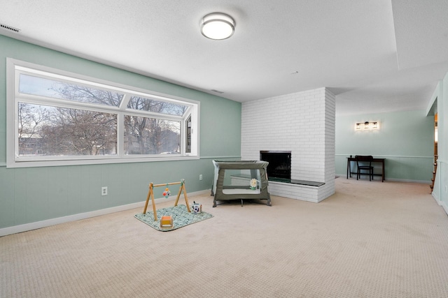 living area with visible vents, a textured ceiling, carpet flooring, a fireplace, and baseboards