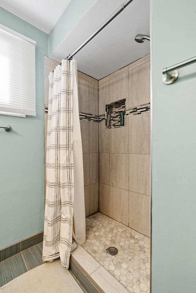 bathroom with baseboards and tiled shower