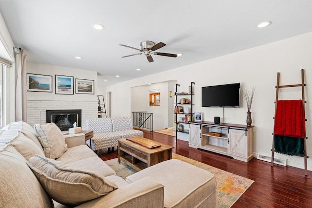 living area featuring visible vents, wood finished floors, recessed lighting, baseboards, and a brick fireplace