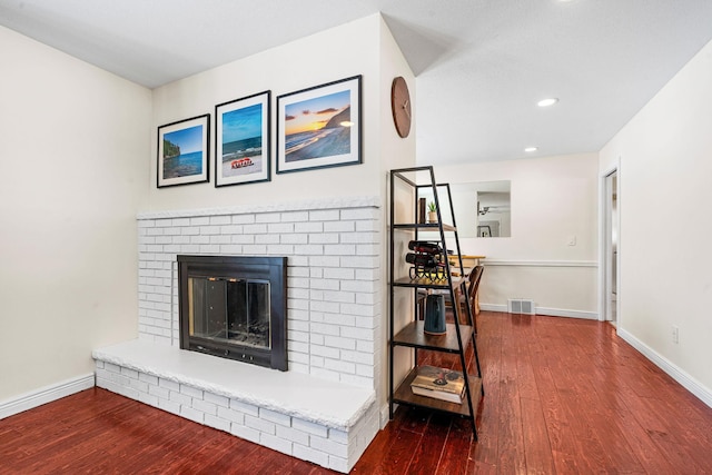 living room with visible vents, a brick fireplace, baseboards, recessed lighting, and wood finished floors