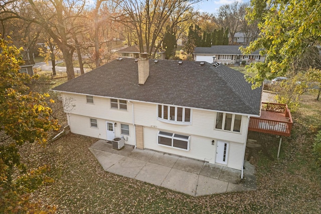 back of property with a deck, a patio area, roof with shingles, and a chimney