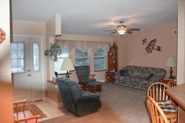 living room featuring light carpet, light tile patterned floors, ceiling fan, and visible vents