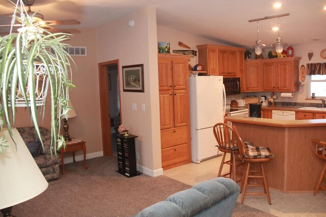 kitchen with visible vents, freestanding refrigerator, a kitchen bar, black microwave, and a sink